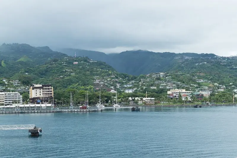Papeete takes yachts alongside its waterfront quay right in front of the town, the hills behind it under low cloud.