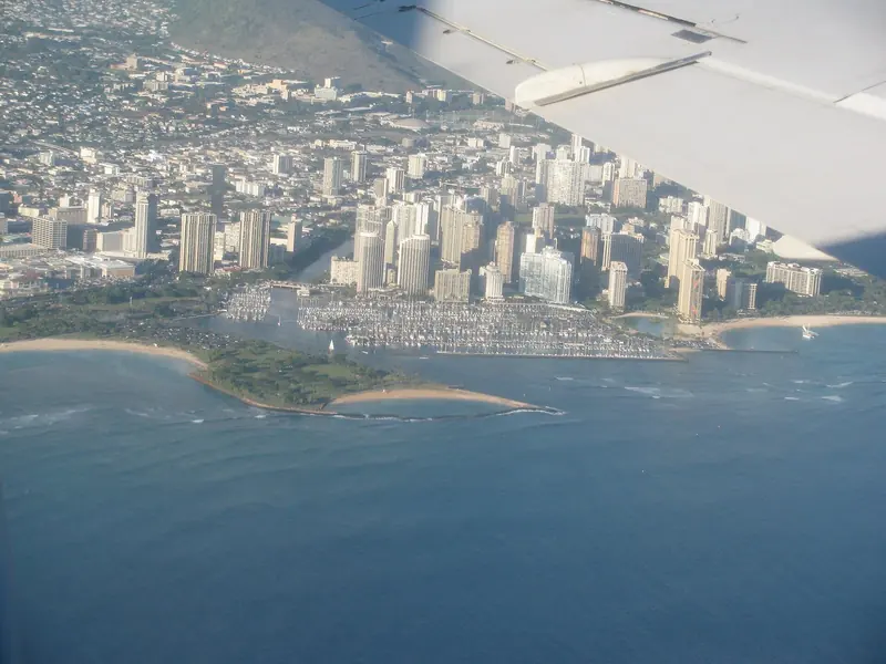 Ala Wai Harbor's full basin from the air: roughly 700 slips packed edge to edge against Waikiki's high-rises, with Magic Island's breakwater and the harbor mouth at bottom left.