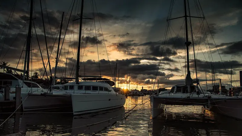 Sunset over Ala Wai Harbor's forest of masts, Honolulu's Kalakaua Avenue towers just visible beyond the breakwater.