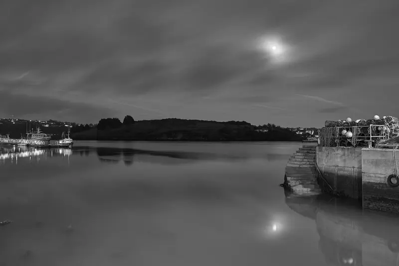 Kinsale harbour at night, working boats alongside the North Pier with lobster pots stacked on the quay