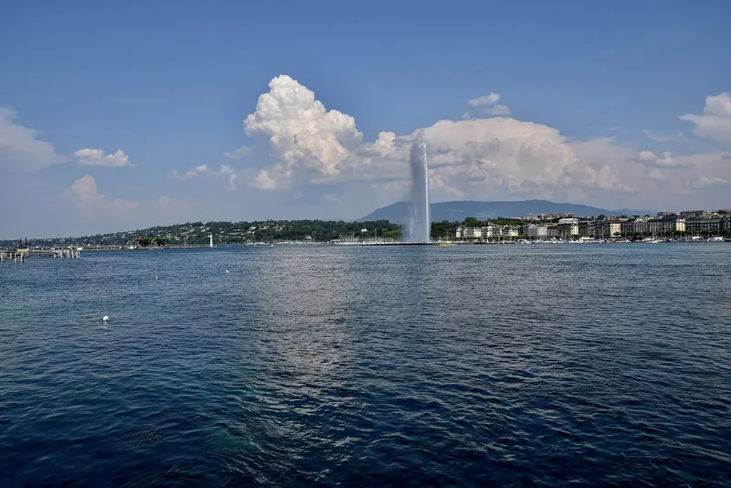 The Jet d'Eau throws water 140 metres into the air over Geneva's harbour, the city's waterfront curving away on either side.