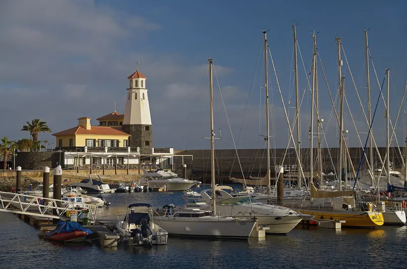 The lighthouse and clubhouse at Quinta do Lorde stand over a forest of masts, the marina's own breakwater closing the pool behind them.