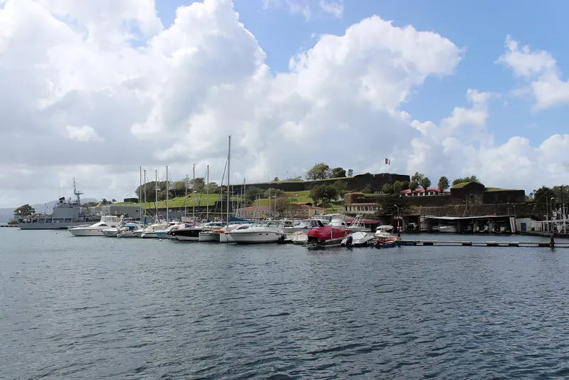 Fort Saint-Louis stands guard over Fort-de-France, Martinique, with yachts and naval vessels moored along the quay below its ramparts.