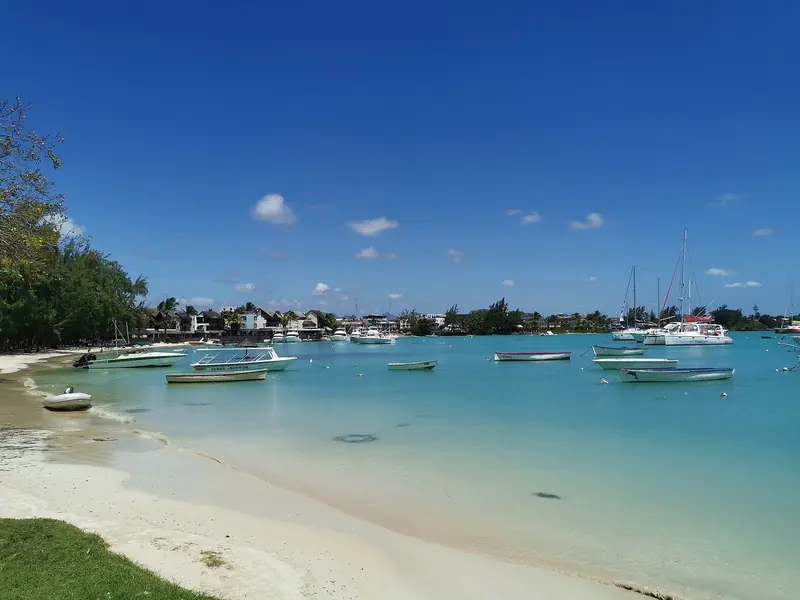 The Grand Baie anchorage at midday, dinghies and day boats moored close to shore with cruising catamarans and sailboats further out in the bay.