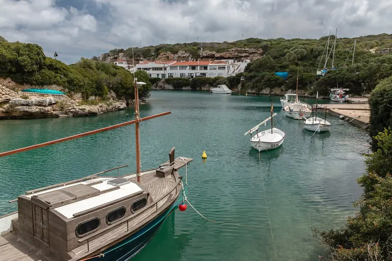 Traditional llaguts and day boats on their moorings at Cales Coves, a fjord-like inlet on the south coast lined with Bronze Age burial caves.