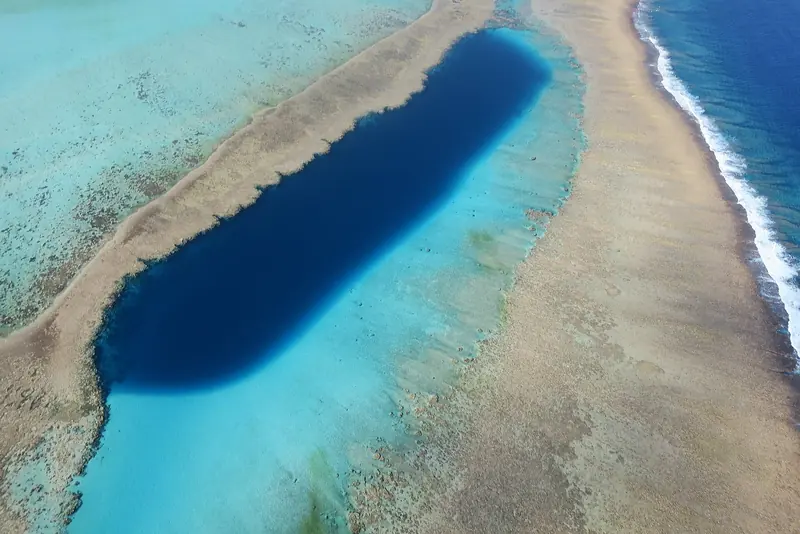 A trou bleu, a blue hole dropping through the barrier reef off Gatope, seen from the air. The lagoon's reef system is the largest in the world after Australia's and is the reason UNESCO listed it.