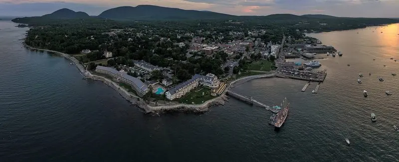 Dusk over Bar Harbor puts the whole anchorage in one frame, moorings off the town quay and wooded hills standing behind.