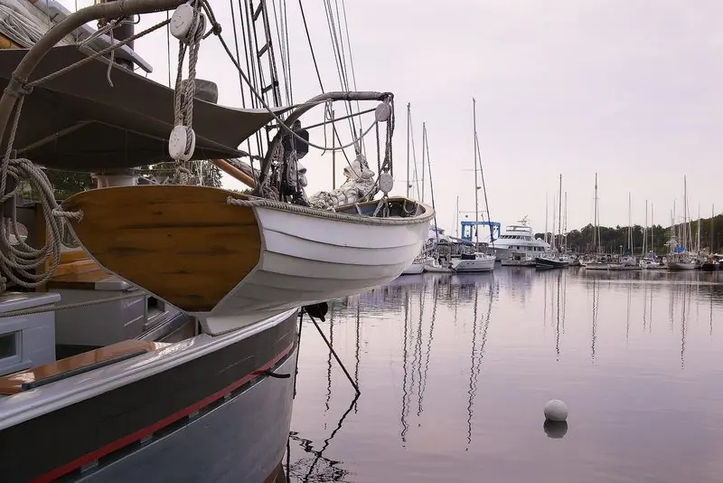 Calm at dawn in Camden, a schooner bow and its wooden dinghy stand over water flat enough to mirror the whole basin.