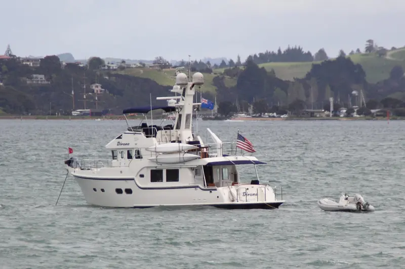 The cruising motor yacht Dirona at anchor off Paihia, with the three-masted former sugar lighter Tui, now a maritime museum ship, in the background.