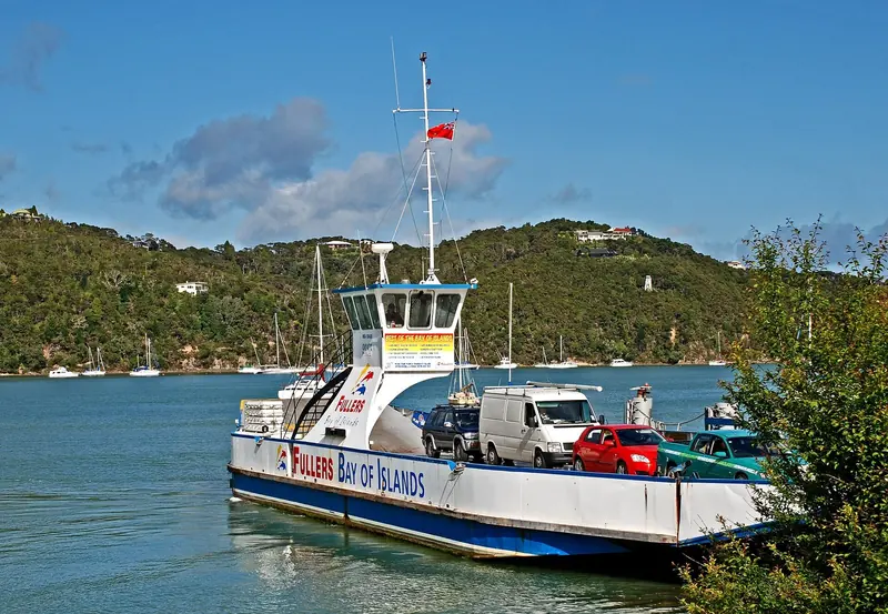 The Fullers vehicle ferry crosses between Opua and Okiato with a line of yachts on moorings behind it, the short hop cruisers use to reach the Russell side of the bay.