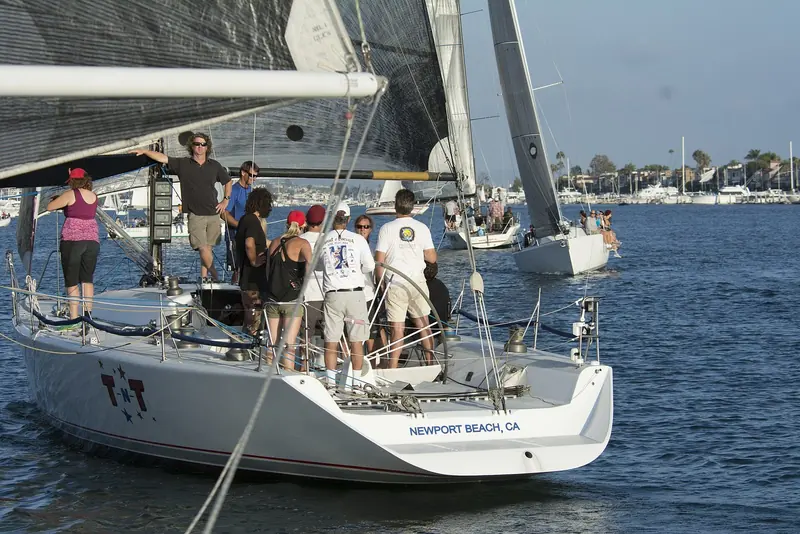 TNT, a Newport Beach-registered racing sloop, working the mark inside Newport Harbor with Lido Isle's docks in the background.