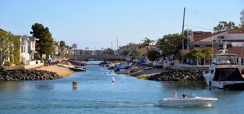 The Grand Canal at Balboa Island, where houses back straight onto the water and small boats sit beached at the tideline.
