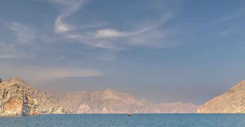 A khor running inland between bare mountain walls in Musandam, deep enough to anchor close under the rock and empty of everything else.
