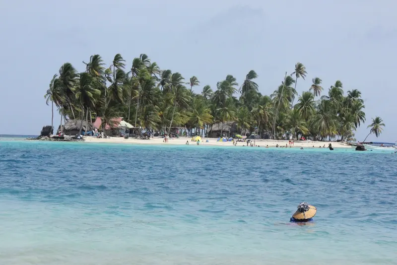 A palm covered sand island in Guna Yala with turquoise water around it, one of about 365 in an autonomous indigenous comarca.