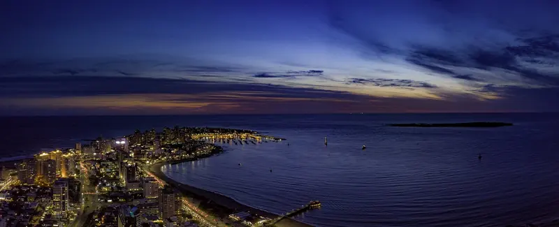 Punta del Este's peninsula lit up after dark, the port and its breakwater visible at the tip where the Rio de la Plata meets the open Atlantic.