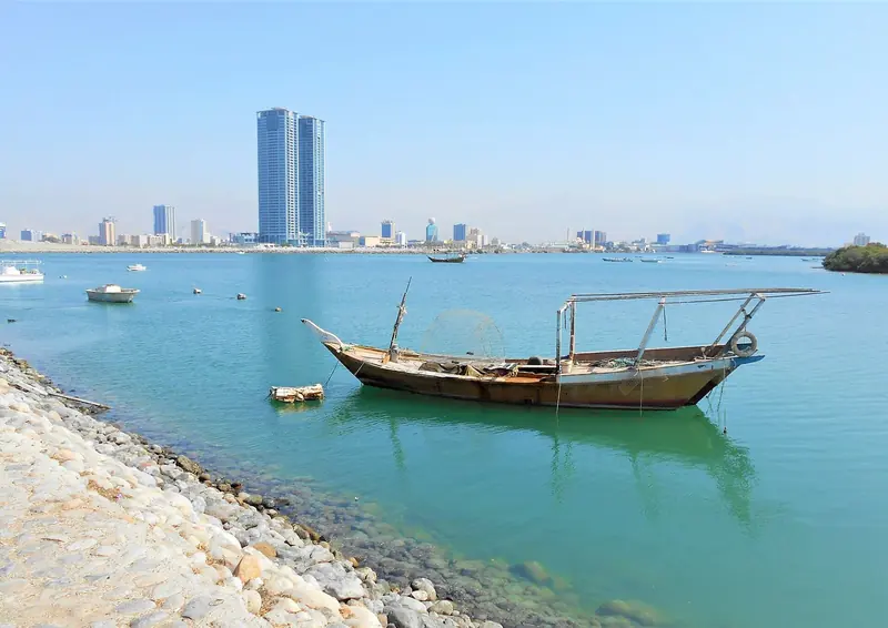 A traditional dhow anchored off the Ras Al Khaimah corniche, with the emirate's skyline behind.