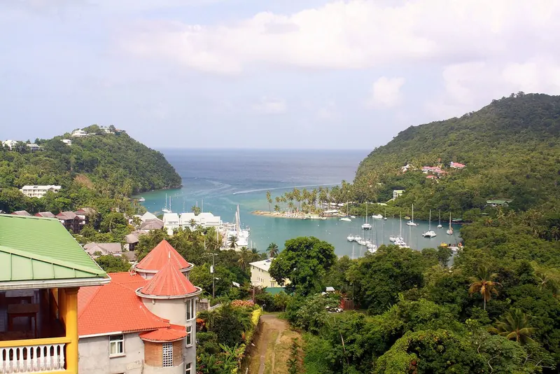 Marigot Bay from the hillside, boats moored in the lagoon below a colonial-style house.