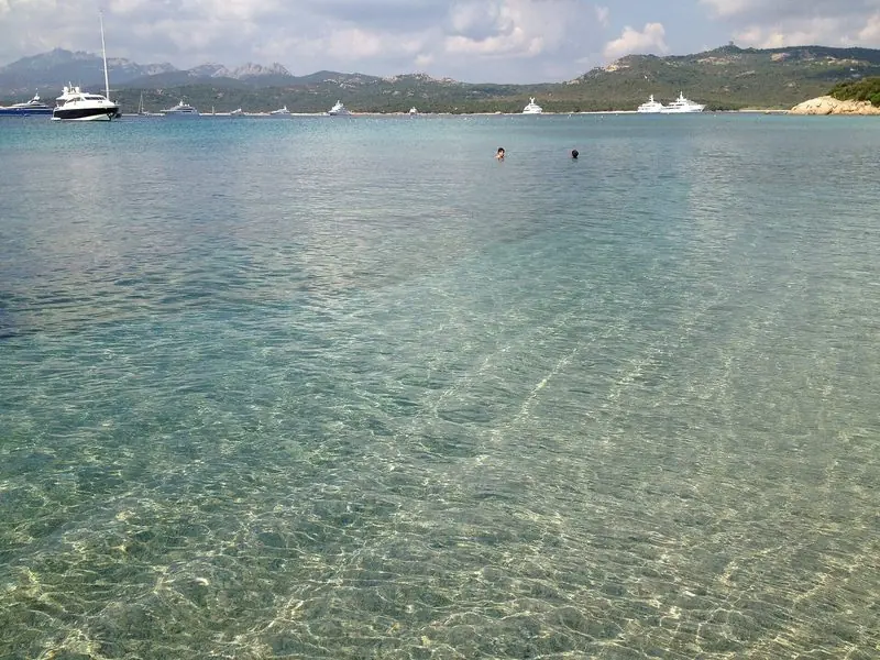 The shallow, clear water of the Costa Smeralda, with yachts anchored off the beach.