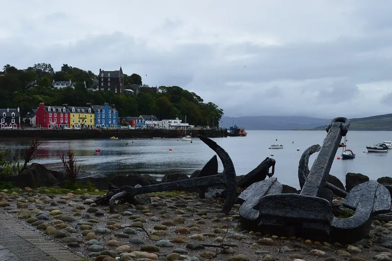 The painted waterfront at Tobermory on Mull, with old anchors on the shore and the pontoon that takes a boat alongside at any state of tide.