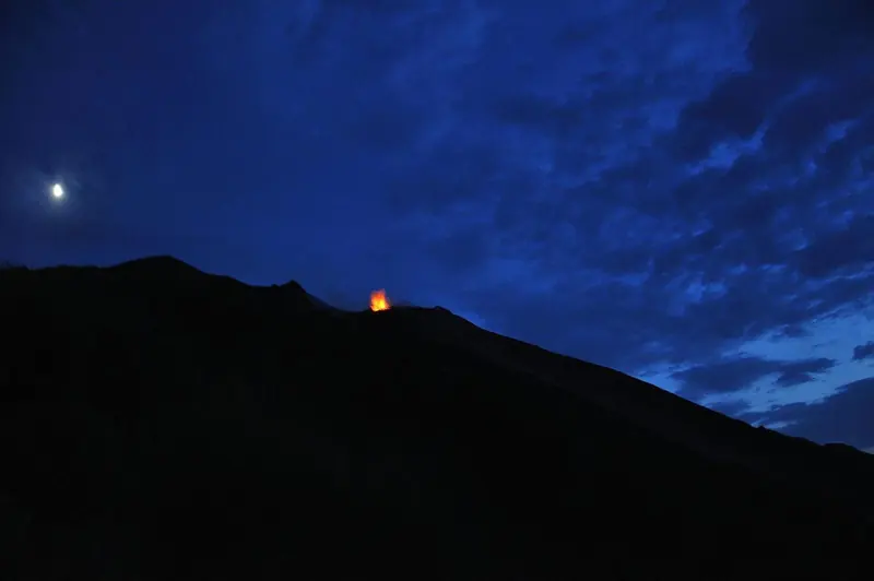 Stromboli at dusk with the summit glow already visible, an island that has been in continuous mild eruption for at least two thousand years.