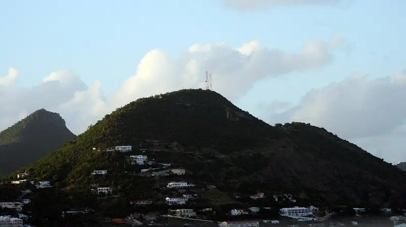 Hillside villas climb toward Sentry Hill above Philipsburg, seen from the water as the island's high ground drops down to the harbour.