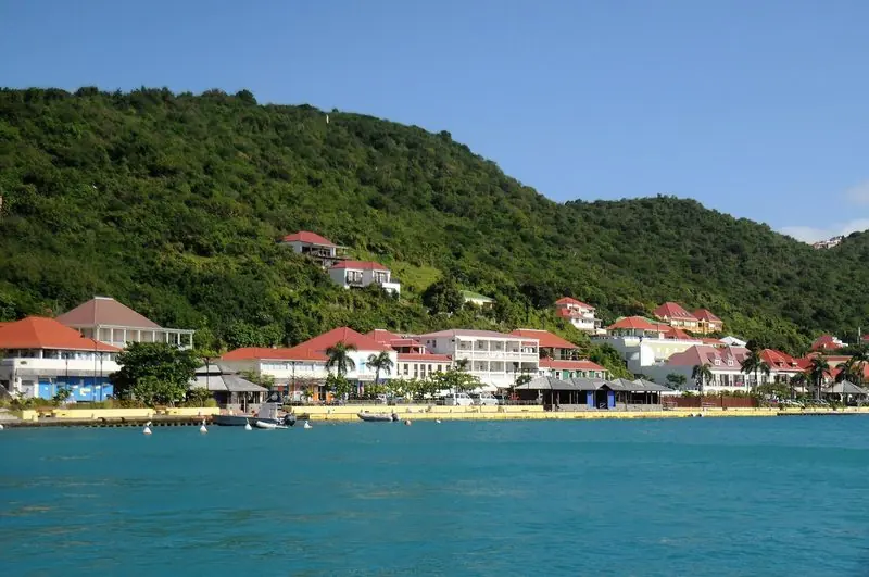 Red roofs and villas climb the hillside above the Gustavia waterfront, restaurants and tender berths lining the seawall.