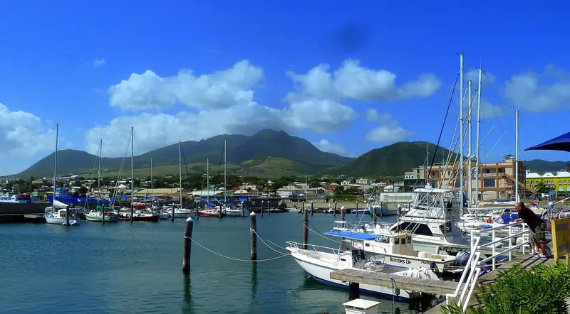 Yachts and sport-fishing boats at the small-boat marina in Basseterre, with Nevis Peak rising across the Narrows behind.