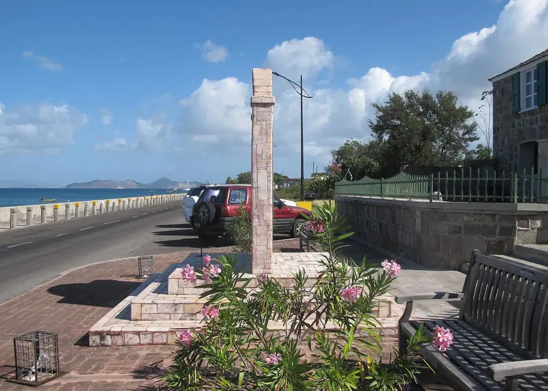 The Charlestown waterfront on Nevis, looking north across the Narrows toward St Kitts, with small craft moored offshore.