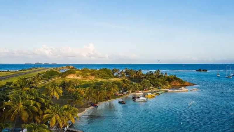 Clifton on Union Island runs its airstrip right down to the shore, work boats pulled up on the beach and yachts lying in the lee of the reef beyond.