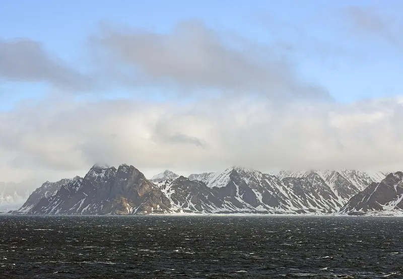 Snow covered mountains along the coast under a summer sky that never darkens between late April and late August.