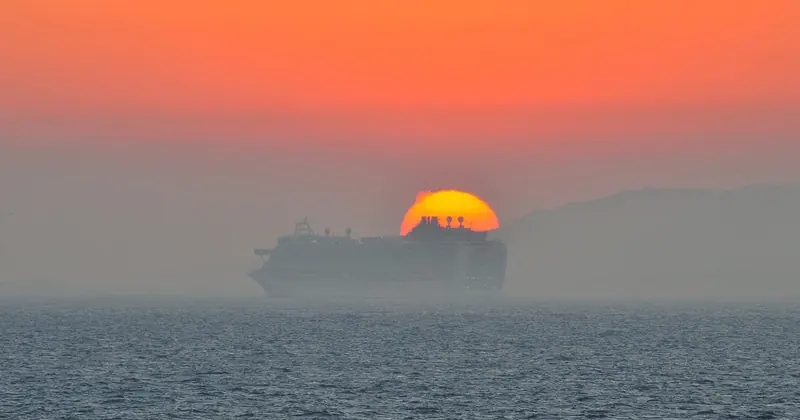 A tanker's silhouette against the sunset in the Strait of Gibraltar, one of roughly 300 commercial vessels a day that cross the traffic separation scheme a yacht has to thread.