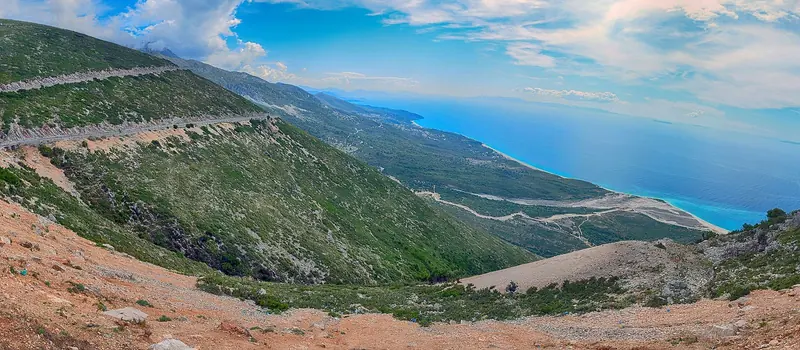 The coastal road over Llogara Pass, the main overland approach to the Riviera from Vlore, dropping toward Palase and Dhermi.