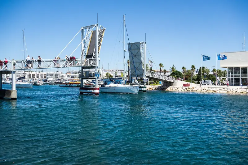 The lifting bridge at Marina de Lagos opens for a yacht, with the old town a walk from the end of the pontoon.