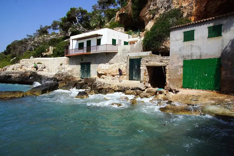 A cove on the Mallorcan coast, old boat houses cut into the rock.