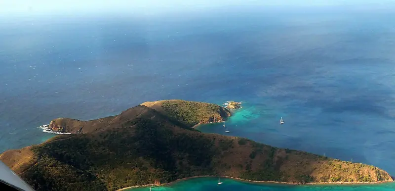 The western end of Norman Island from the air, with the anchorage in the lee and the Sir Francis Drake Channel running away beyond it.