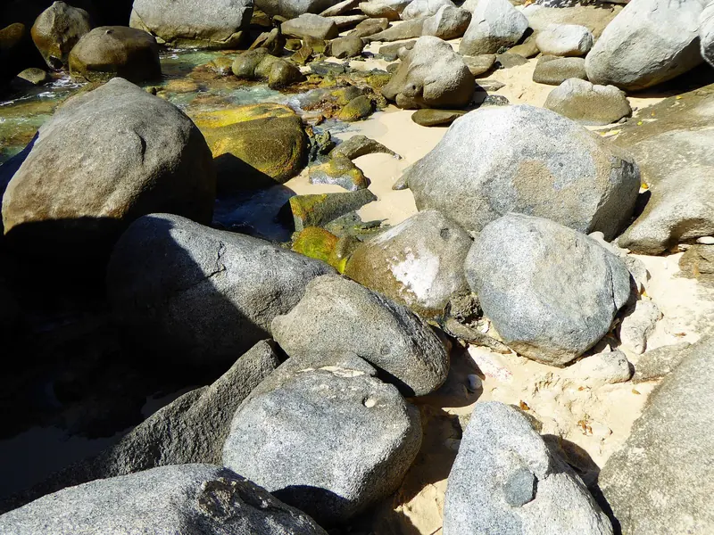 Pale sand between the boulders at the Baths, where the day mooring field fills by mid morning and no overnight stay is allowed.