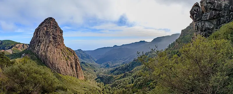 Volcanic rock towers above the forested interior of one of the western islands, which are steep, green and almost empty.
