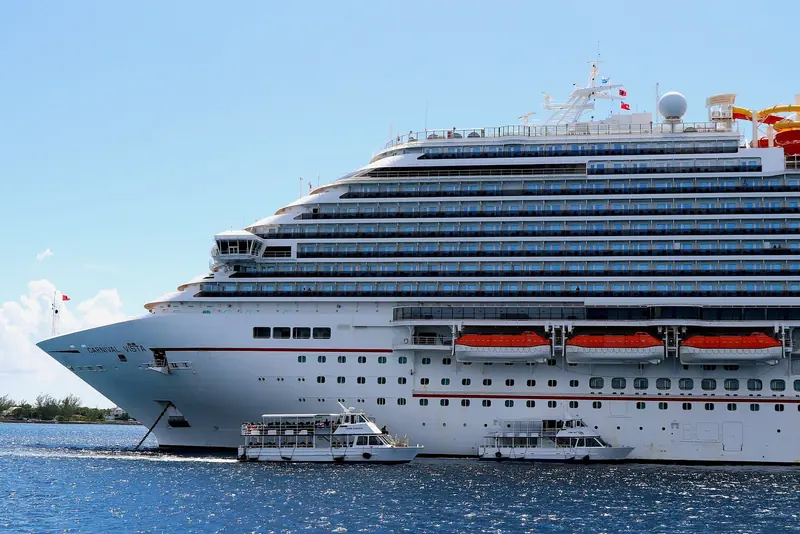 Carnival Vista anchored off Grand Cayman with two tender boats alongside, the everyday reality of a coast with no deepwater cruise pier.
