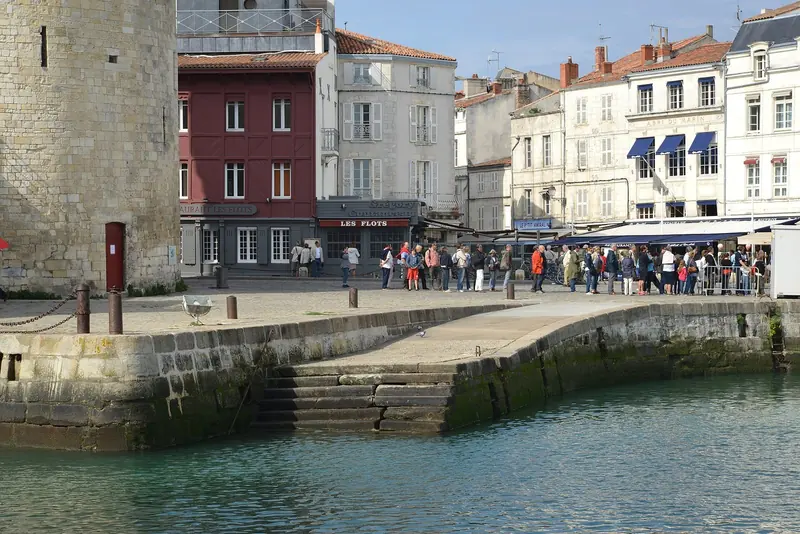 Cafe tables line the Escalier des Sardiniers at La Rochelle's fishing harbour, packed with visitors on a high-tide afternoon.