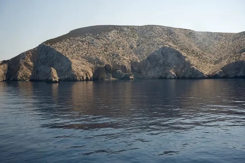 The bare cliffs of the western Cyclades, seen from a boat working up the coast.