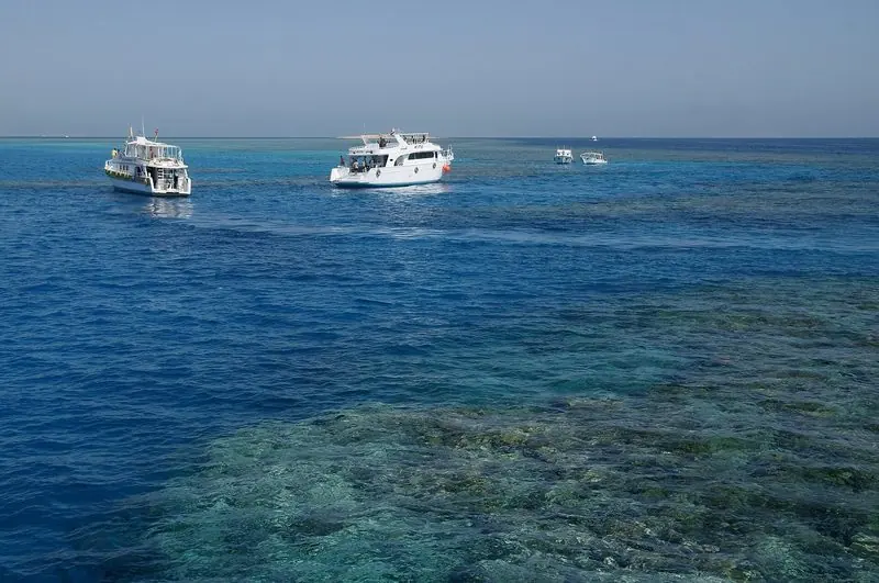 Cafe tables line the quay at El Gouna, where catamarans and motor yachts lie in a basin closed off from the open Red Sea by a rock breakwater.