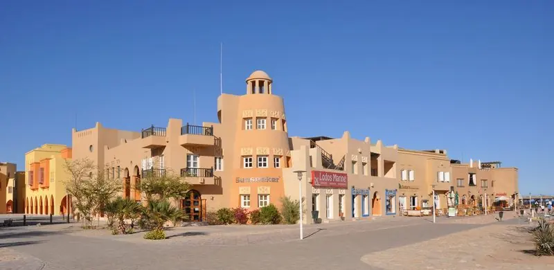 Ochre blockwork and a domed tower front the square, where chandlery and brokerage sit in the same row as the restaurants.