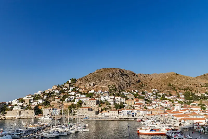 Hydra's harbour curls into a tight stone amphitheatre, small boats lining both quays and whitewashed houses stacked up the hillside behind.