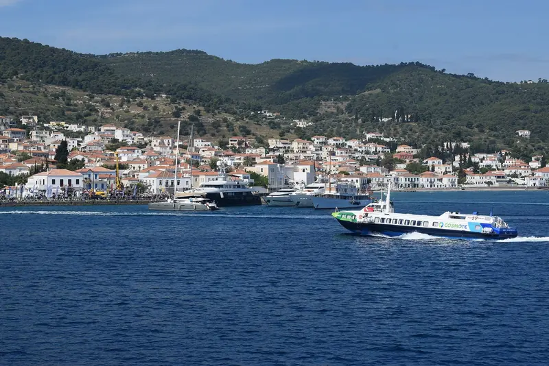 An inter-island ferry approaches Spetses, the town's white and ochre houses rising above its own small harbour.