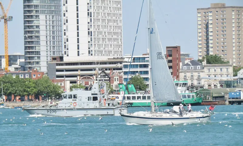 A yacht comes into Portsmouth harbour past the naval traffic, one of the two entrances that give the Solent its double high water.