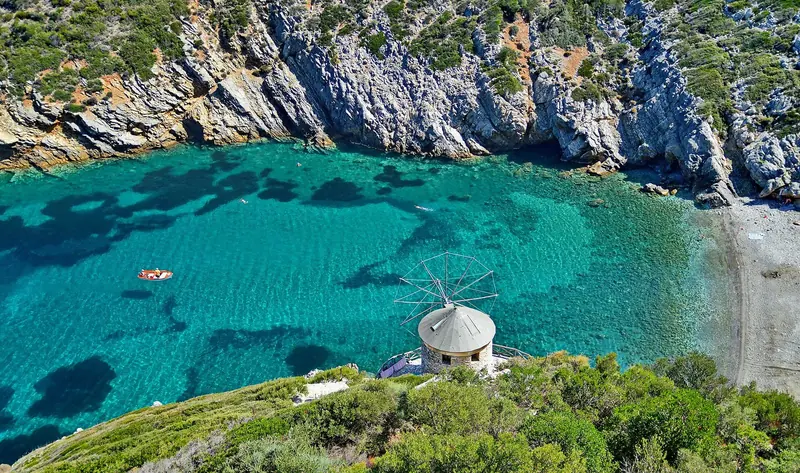 A windmill above a turquoise cove on Alonissos, at the edge of the marine park's protected waters.
