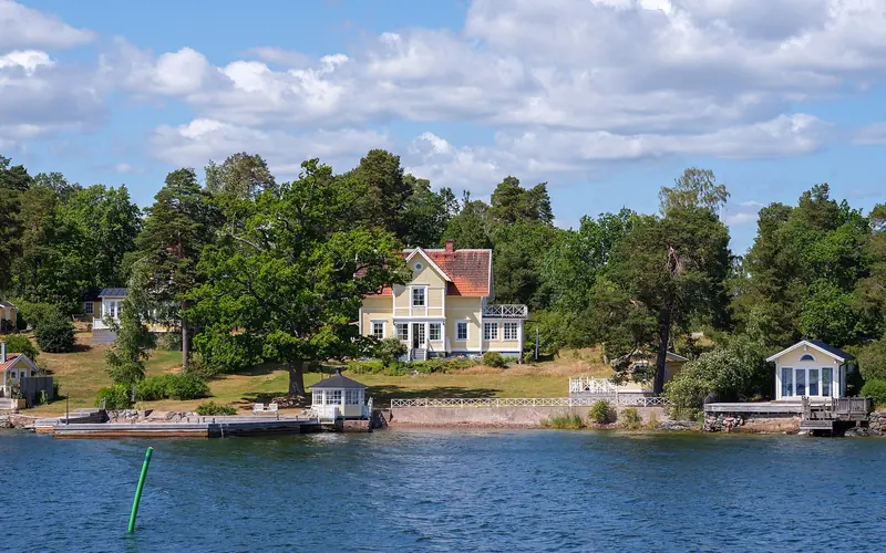 Red summer houses on a wooded shore, the pattern of the inner archipelago where every island of any size has a jetty.