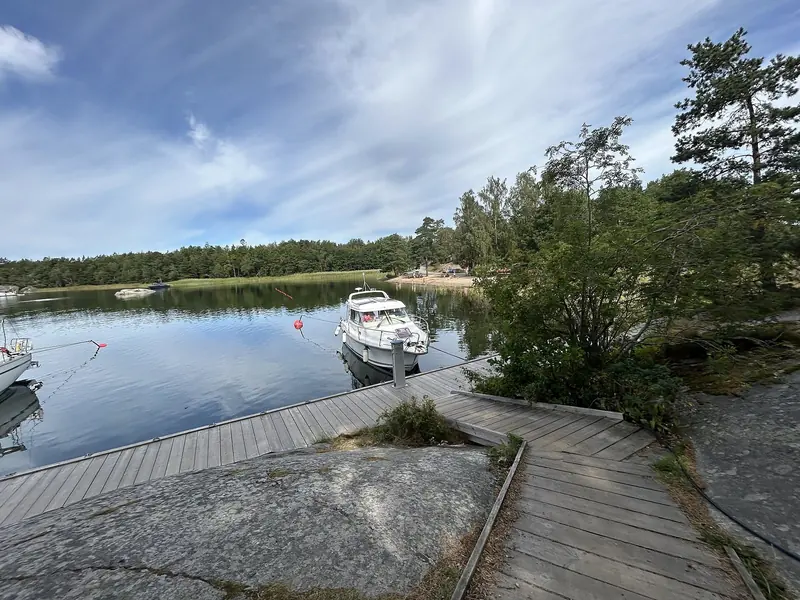 A motor boat lies bow to the rock in a sheltered inlet, which is how the archipelago is used: an anchor astern and a line ashore.