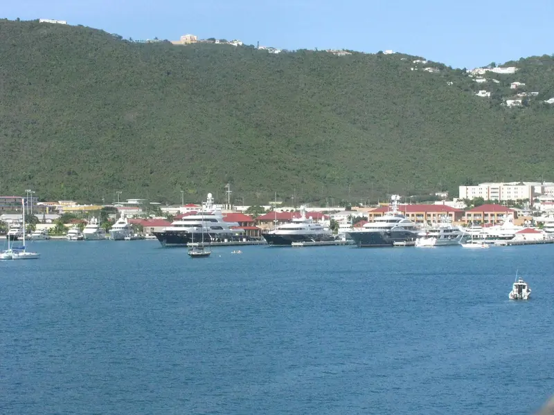 Charlotte Amalie harbour, St Thomas, seen from a departing cruise ship: megayachts on the town pier below Yacht Haven Grande, a sailboat on a mooring, and a launch running between them