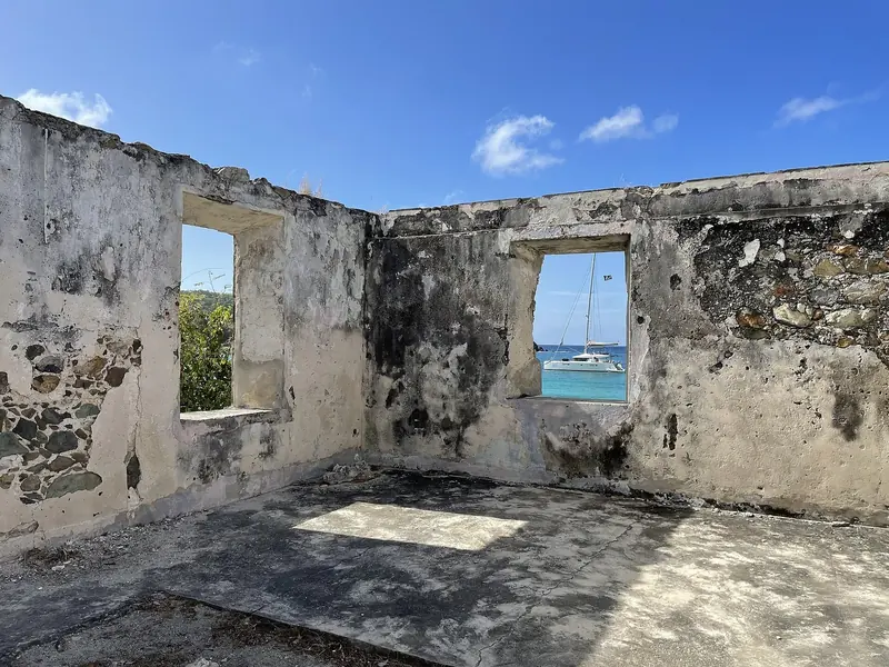 The same Lameshur Bay anchorage on St John framed through a ruined plantation window, the national park's history and its cruising ground in one shot
